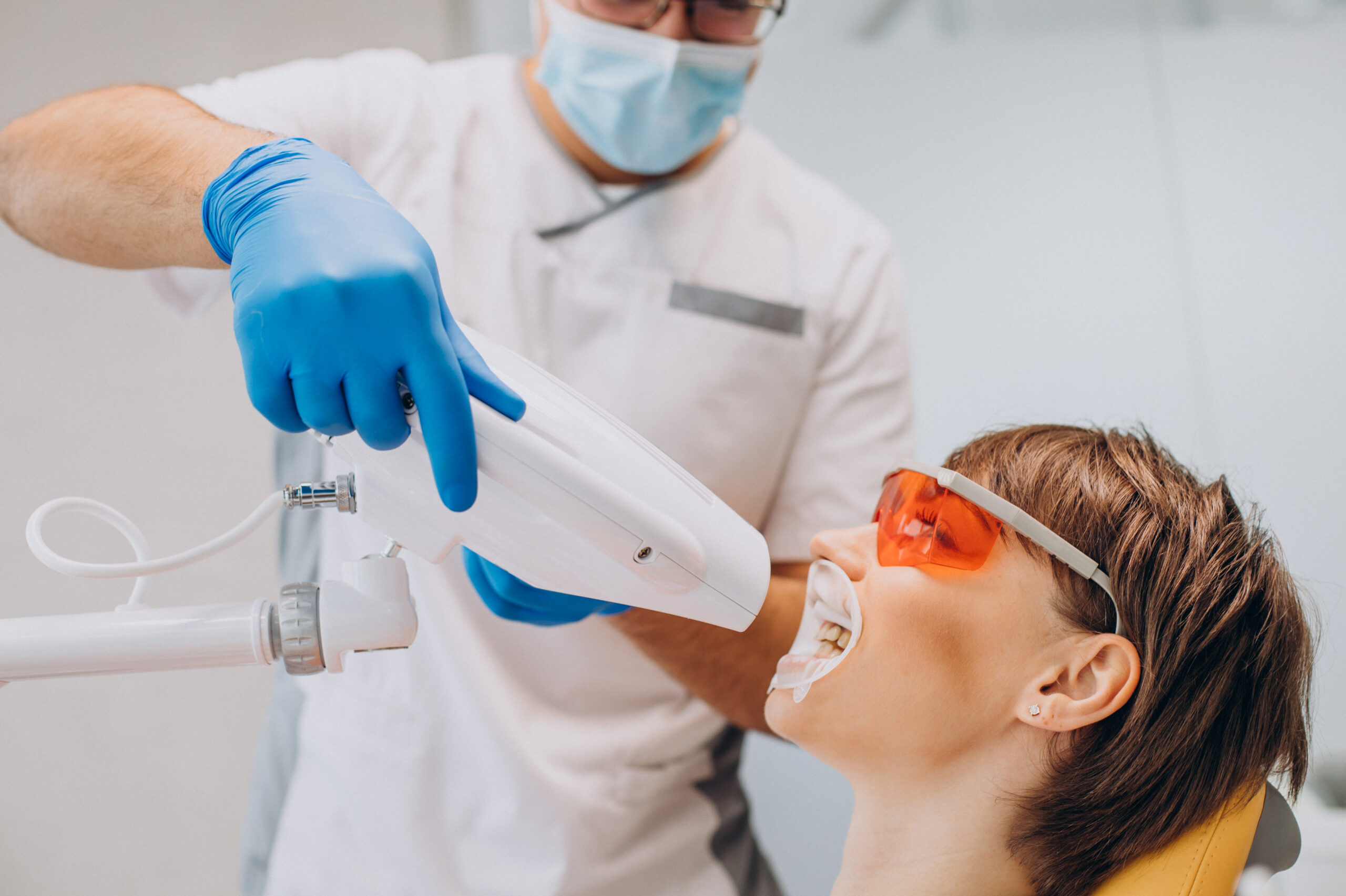 Mulher fazendo clareamento dental em uma clínica odontológica, com equipamentos modernos.