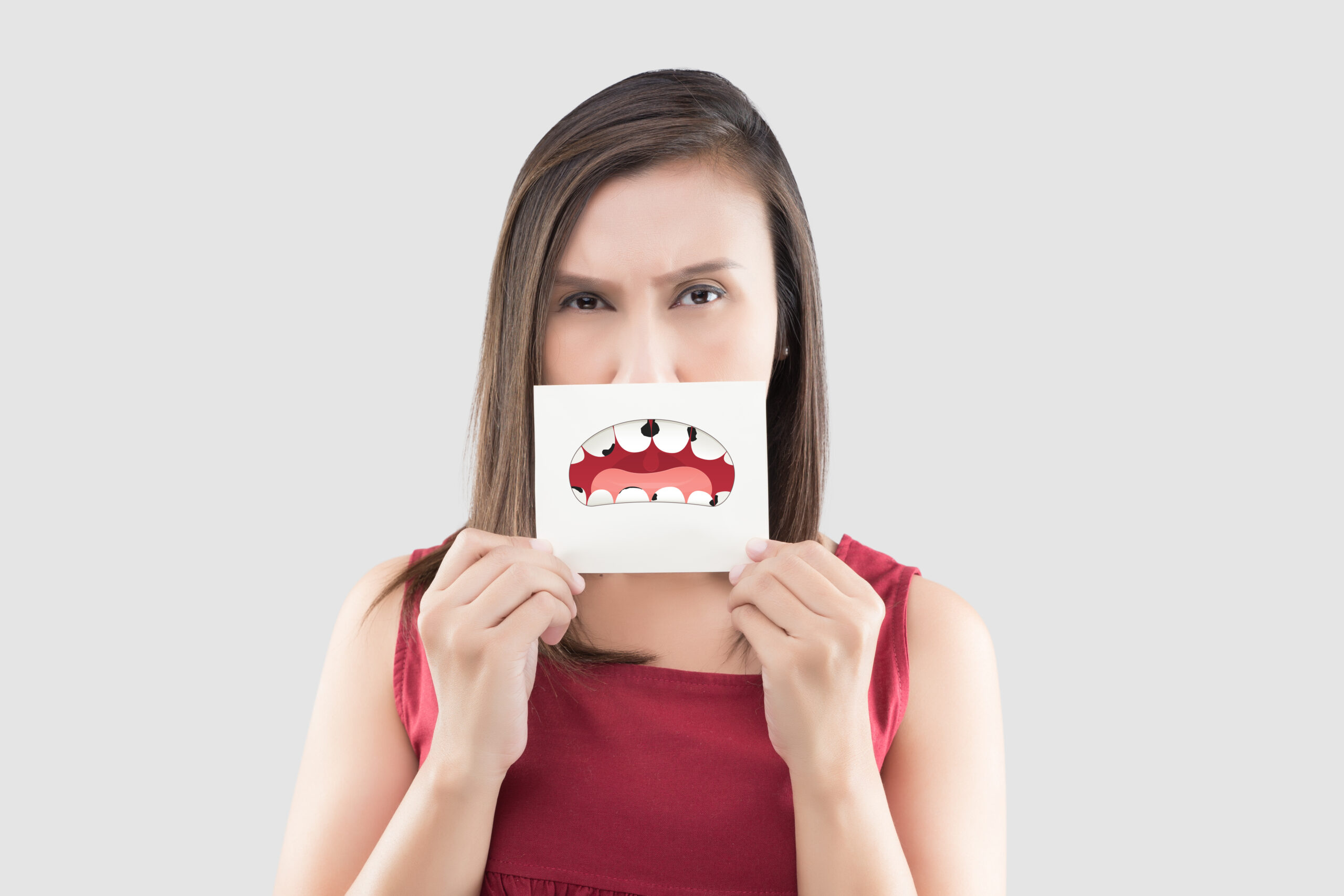 Mulher segurando um cartão onde estão desenhados dentes afetados pela cárie dentária.