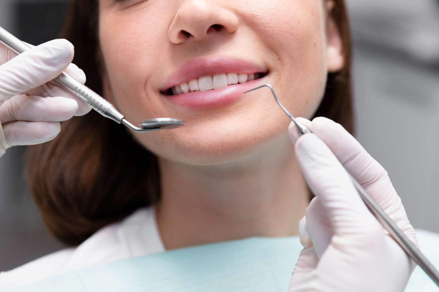 Imagem mostrando o sorriso de uma mulher e, à frente, instrumentos de dentista. Imagem ilustrativa sobre saúde bucal para gestantes.