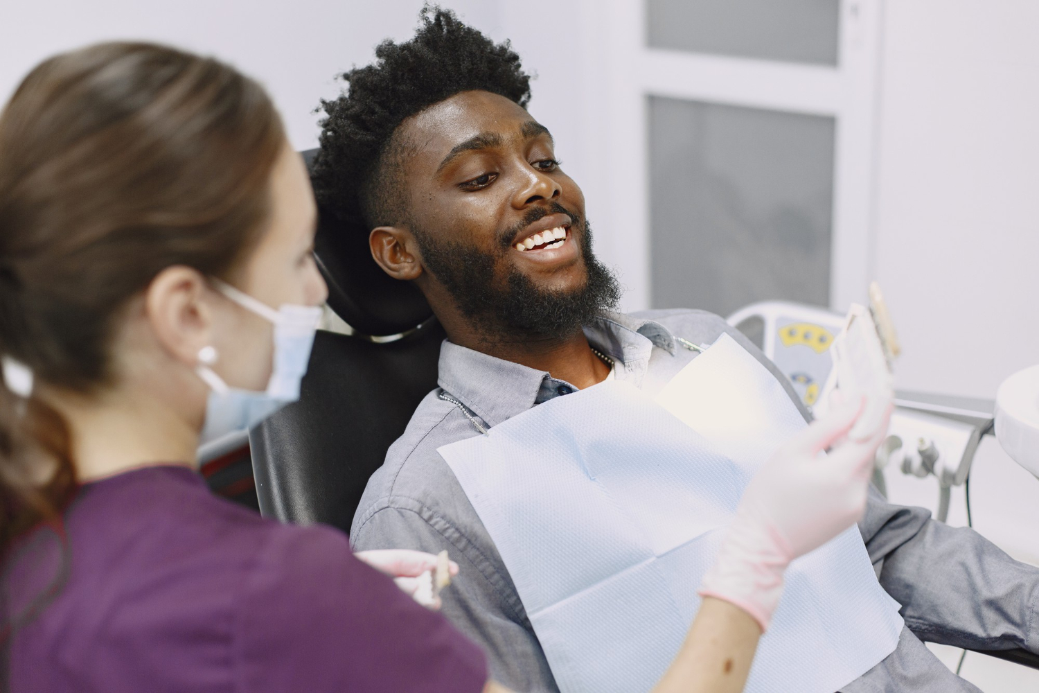 Imagem ilustrativa sobre orçamento para tratamentos odontológicos mostrando um jovem negro sendo atendido por sua dentista, onde discutem o valor dos tratamentos a serem realizados.